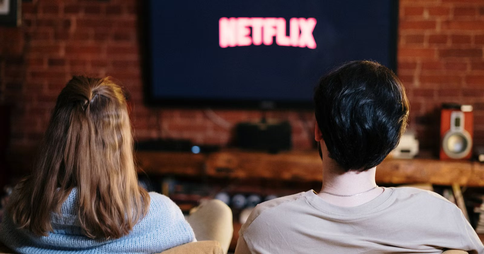 Pareja en sillón viendo Netflix en pijamas